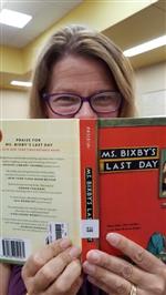 MariIee Thompson with the Ms. Bixby's Last Day book covering lower half of her face
